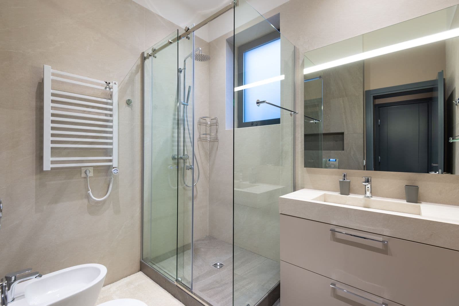 A clean modern bathroom with a glass shower enclosure, vanity unit and polished mirror.