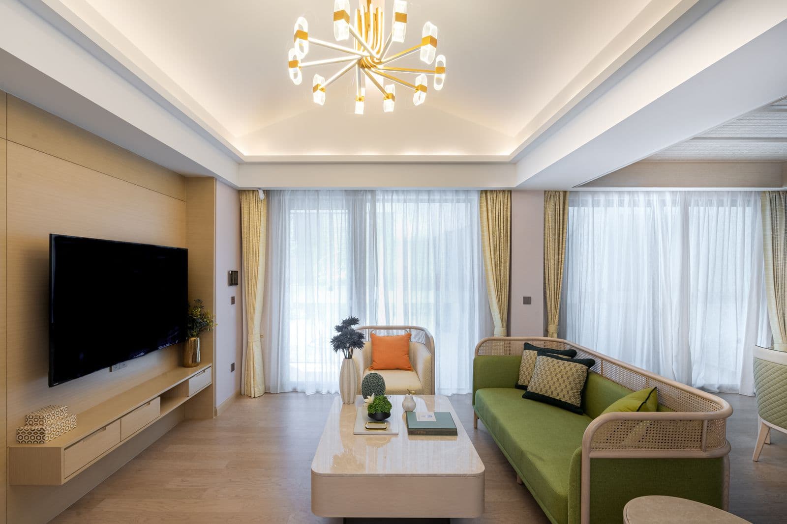 A bright, freshly cleaned living room with a sofa, low table and floor-to-ceiling curtains.