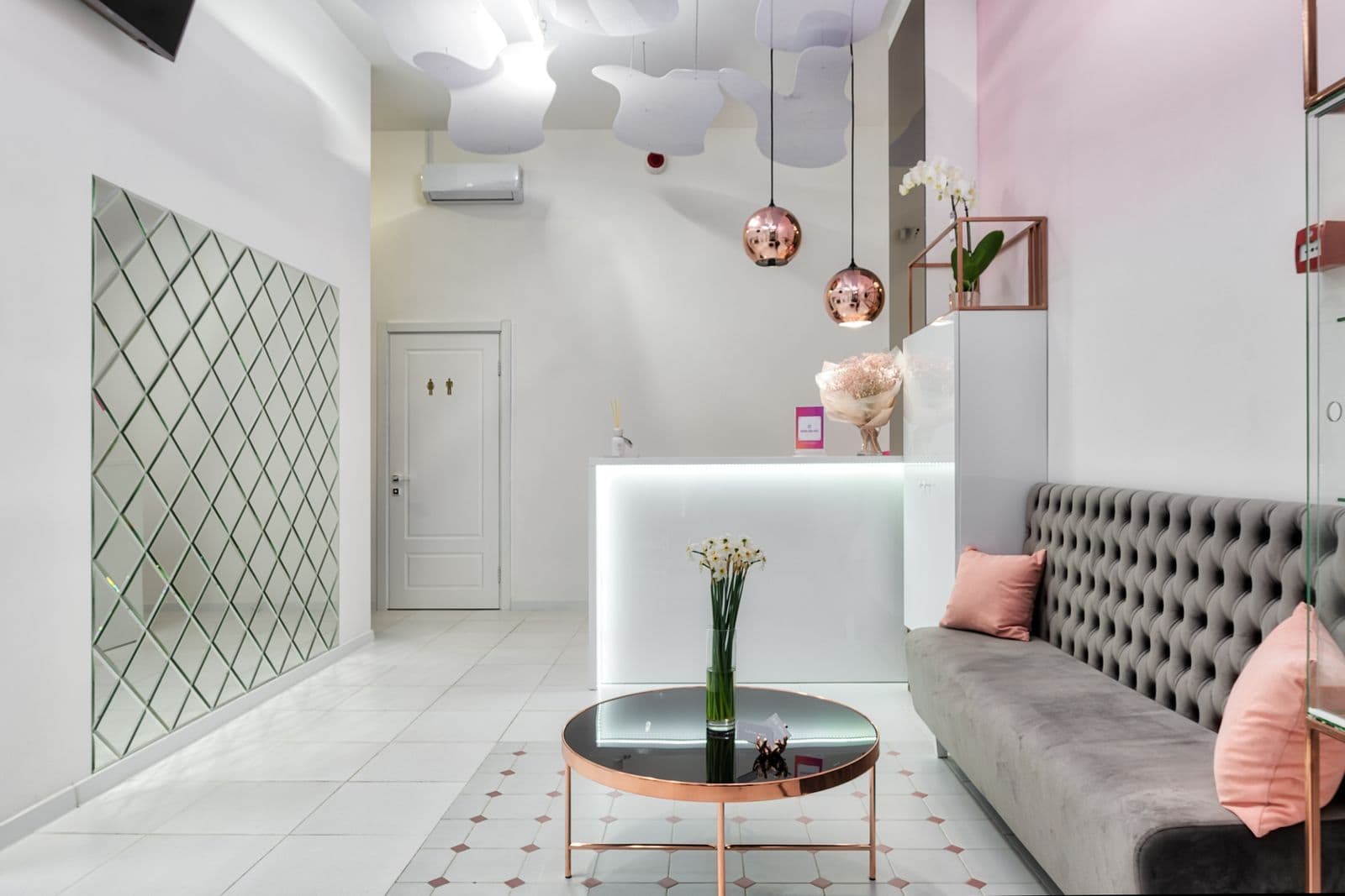A tidy reception area with a lit front desk, seating and a polished floor.